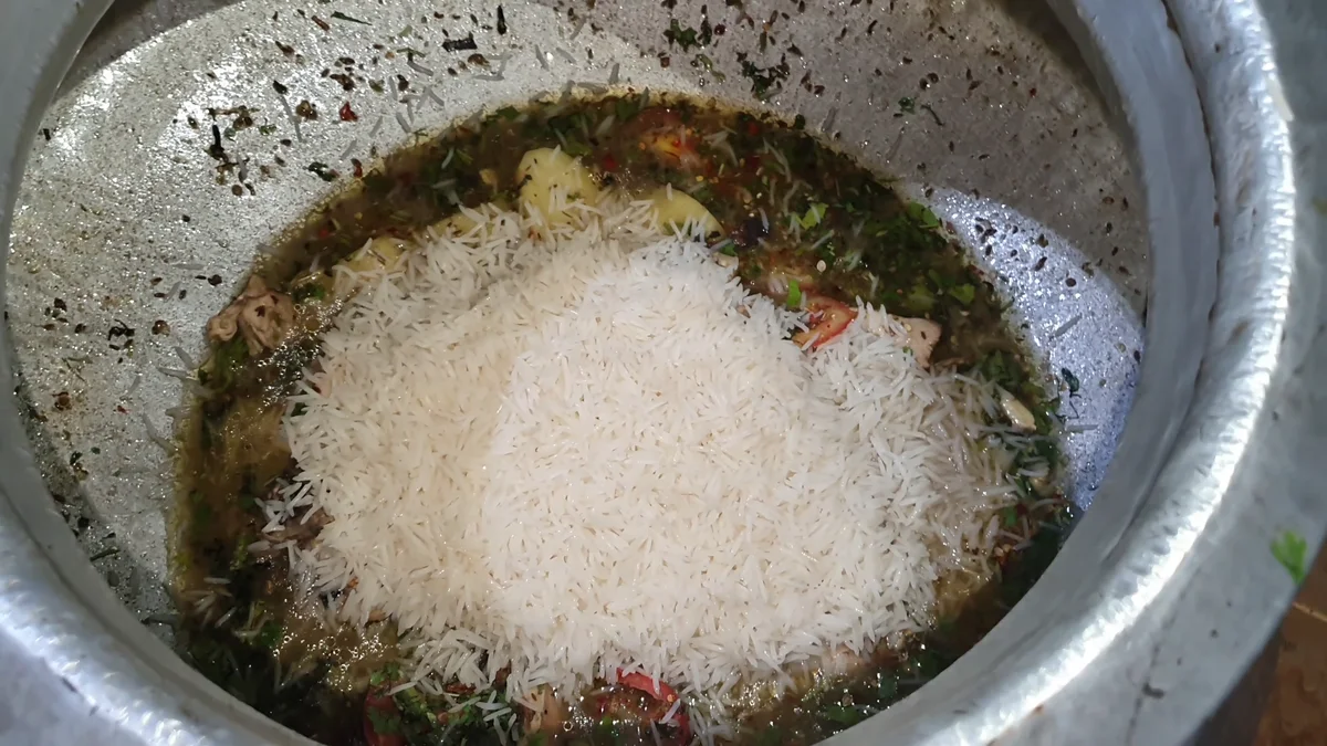 Rice spread over the chicken gravy in the deg