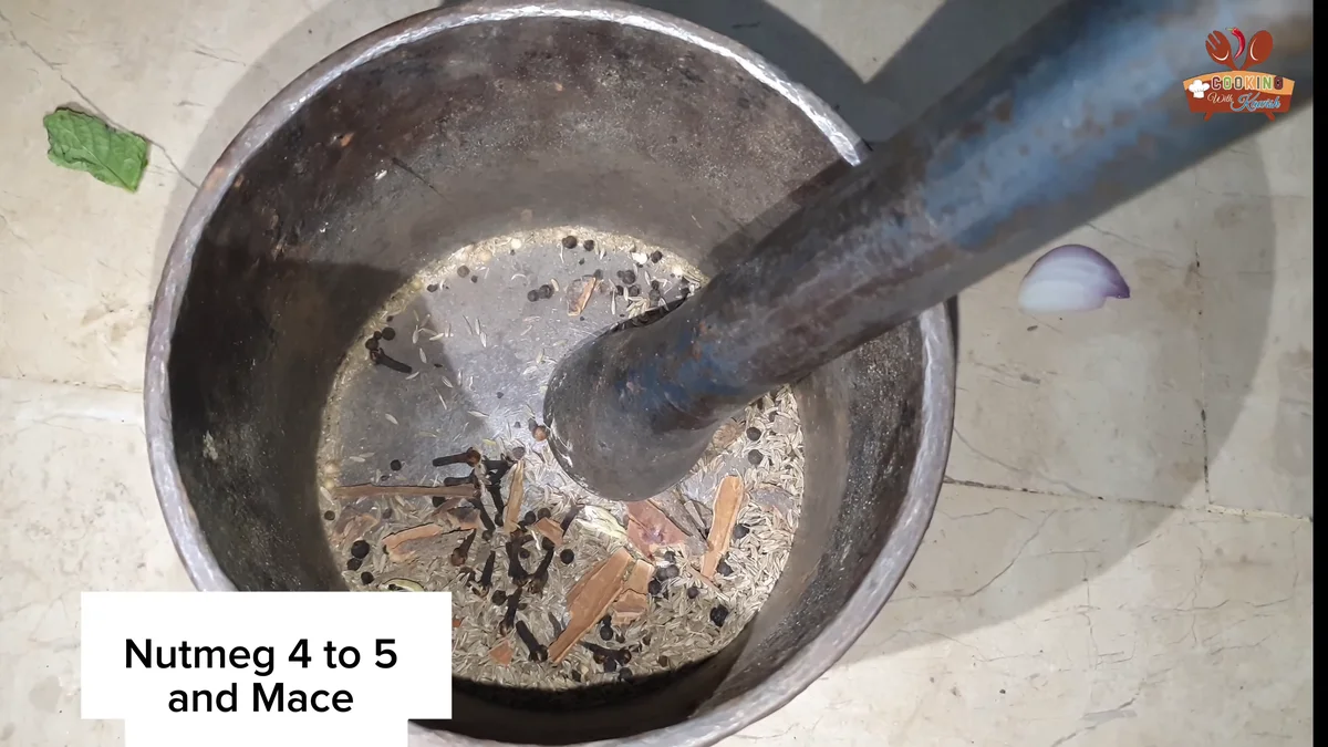 Crushing nutmeg and spices with a pestle for the kunna masala