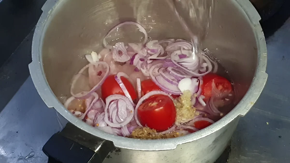 Chicken, onion and tomato with water and oil in the pressure cooker