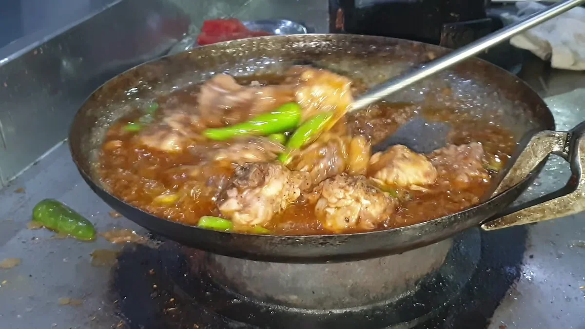 Chicken karahi with green chillies being roasted on high heat