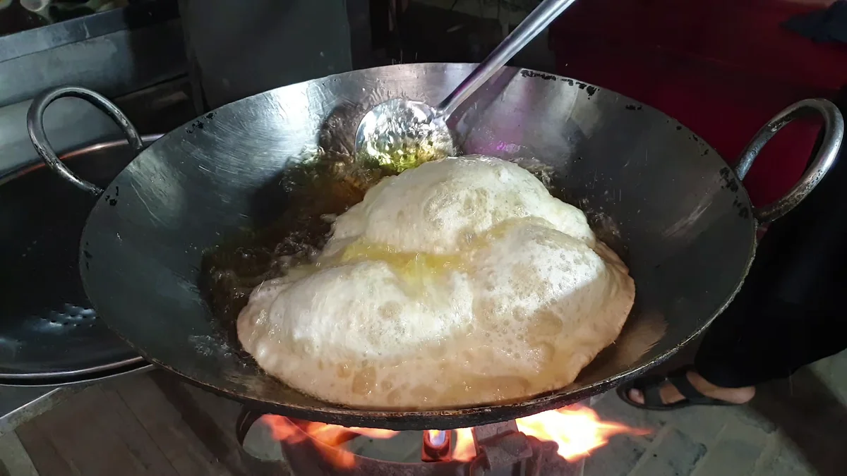 Poori paratha puffing up in hot oil in a karahi