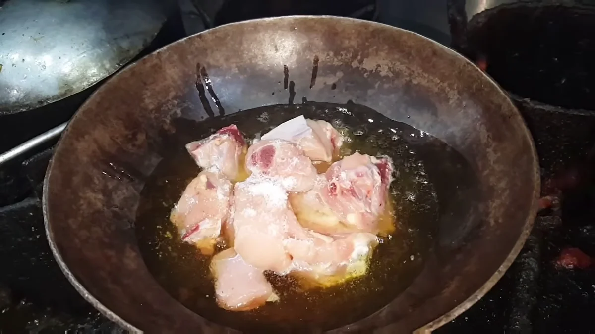 Chicken pieces going into the hot oil