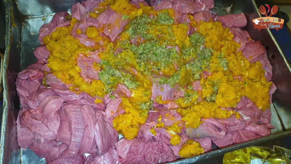 Green paste added over the orange paste on the beef strips