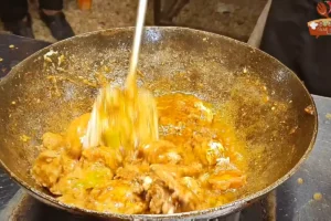Cream being stirred into chicken karahi