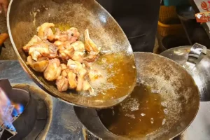 Browned chicken lifted out while extra oil is drained