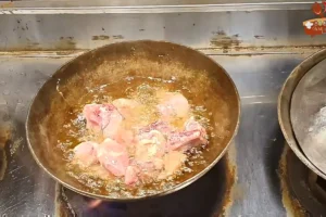 Chicken pieces frying in oil in a karahi