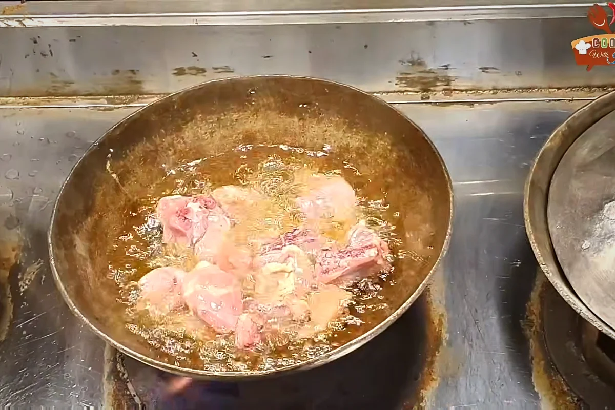 Chicken pieces frying in oil in a karahi