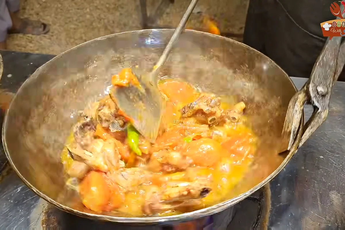 Softened tomatoes being mashed into the karahi gravy