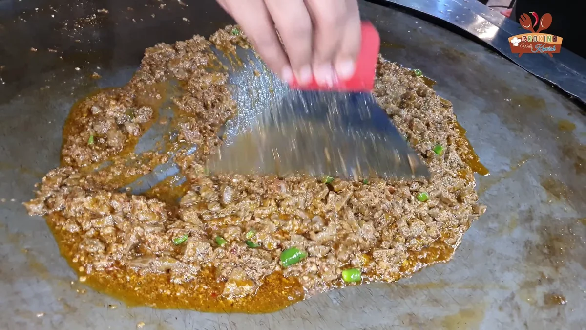 Tossing the tawa fry kaleji with a spatula