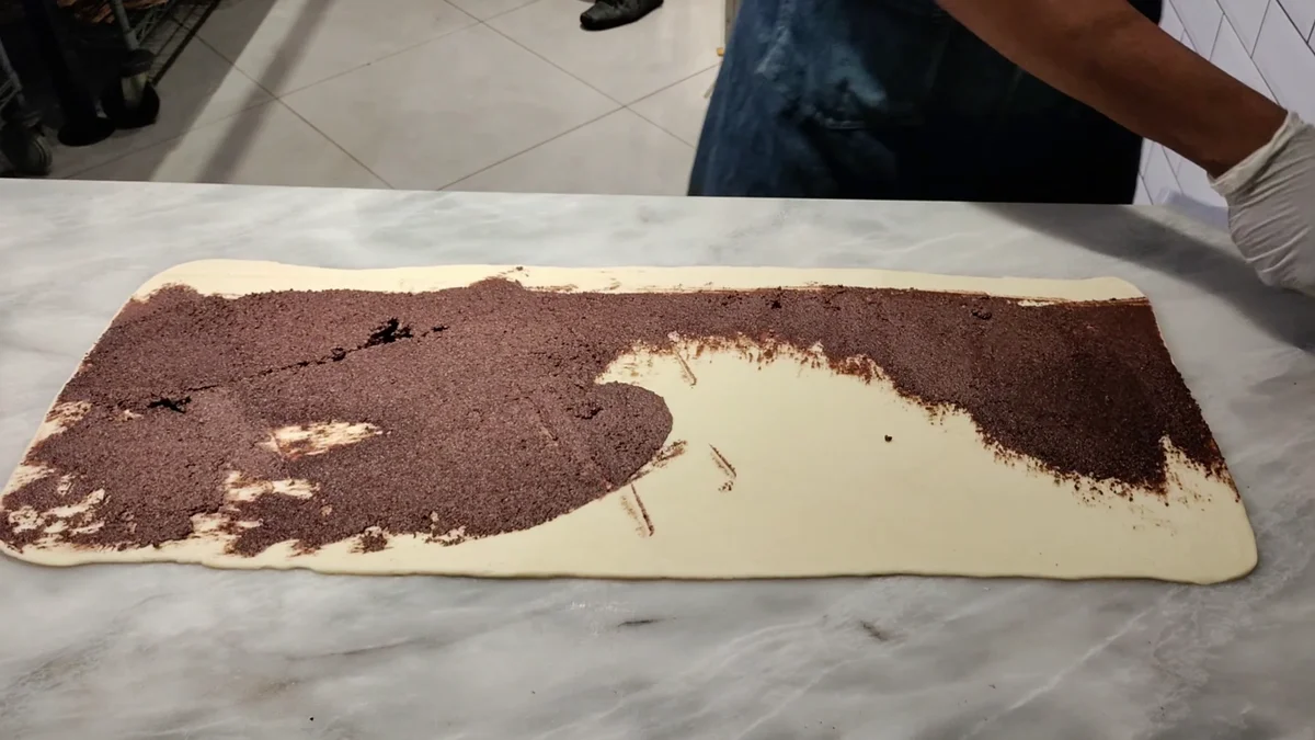Spreading the brown cinnamon filling over the dough sheet