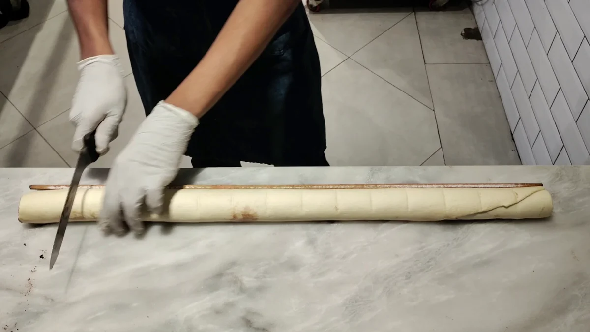 Cutting the dough log into equal rolls with a knife