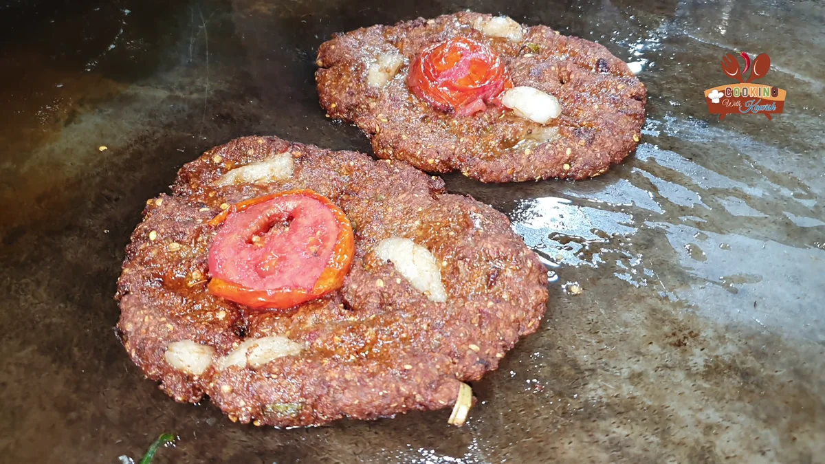 Shaped mutton chapli kababs with tomato slices on a tray