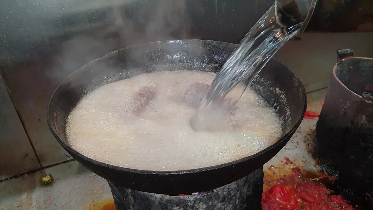 More water being poured into the boiling mutton