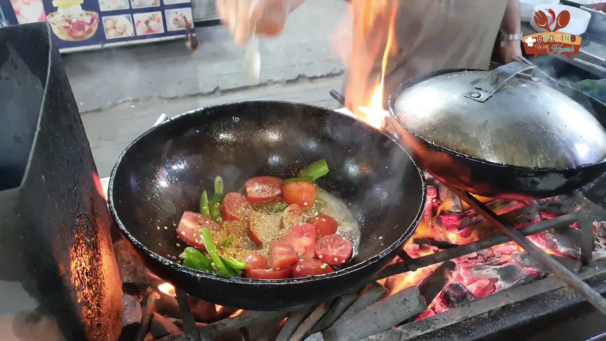 Halved tomatoes and green chillies in the karahi