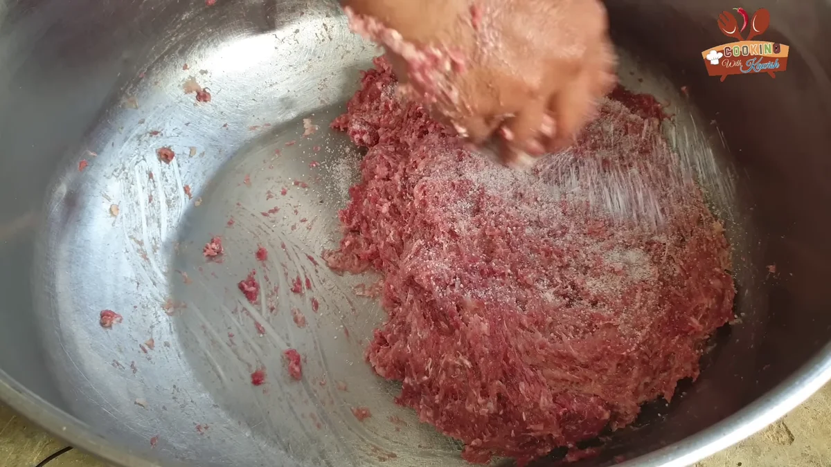 Kneading beef mince by hand in a large steel vessel