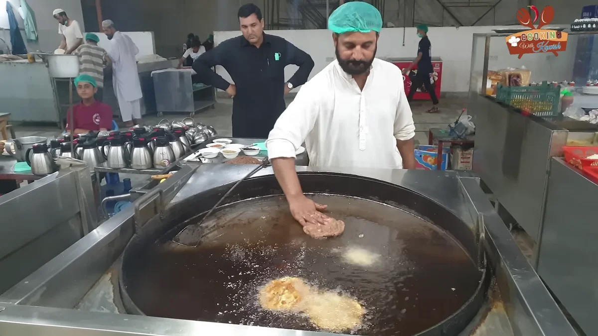 Cook frying chapli kababs in a large pan of ghee