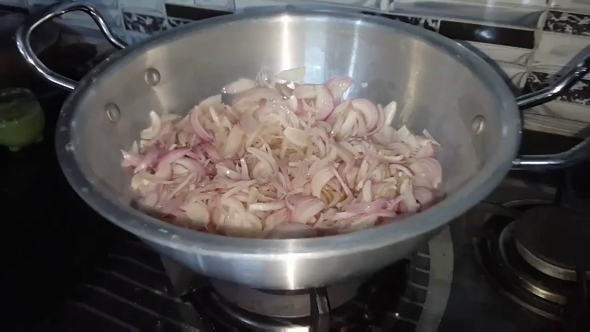 Sliced onions in a karahi to be fried