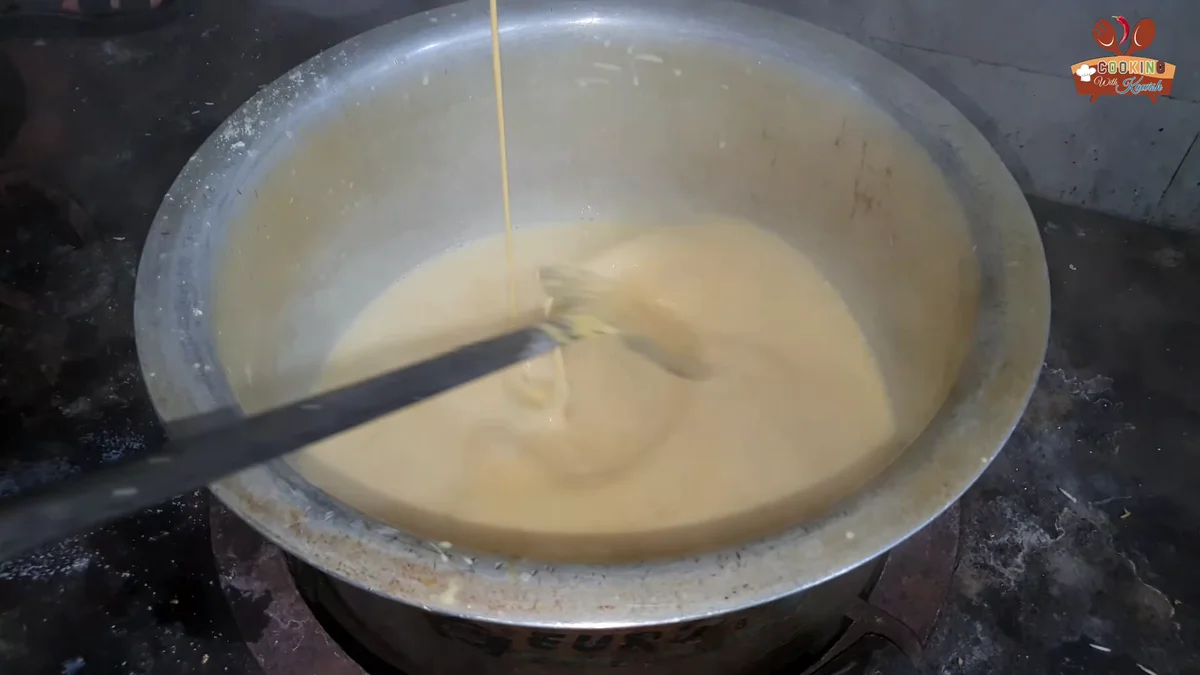 Custard mixture being poured into the boiling milk in a thin stream