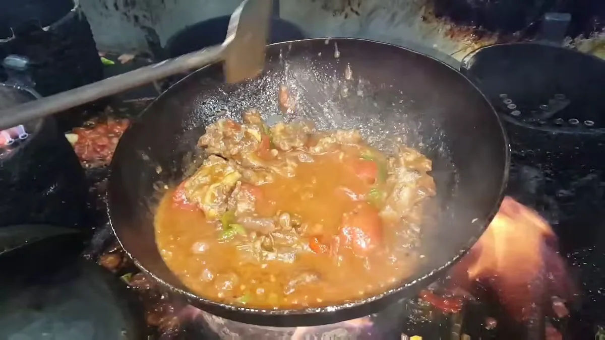 Tomatoes cooking into the karahi gravy