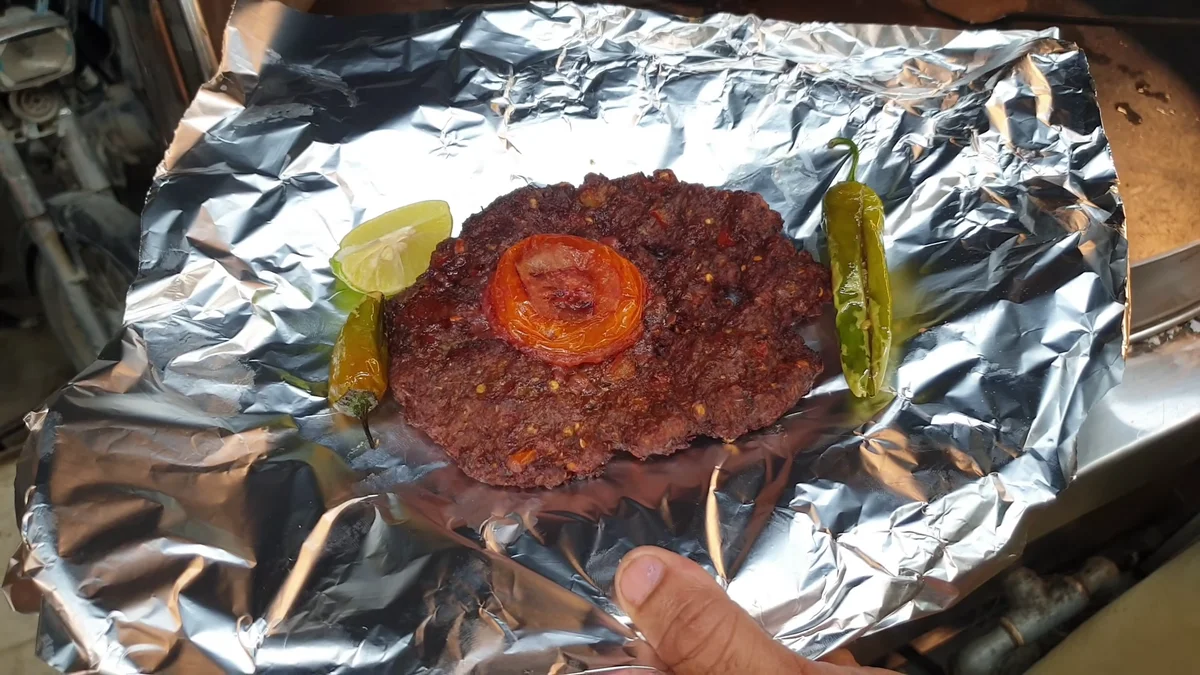 Peshawari chapli kabab served on foil with lemon and green chilli