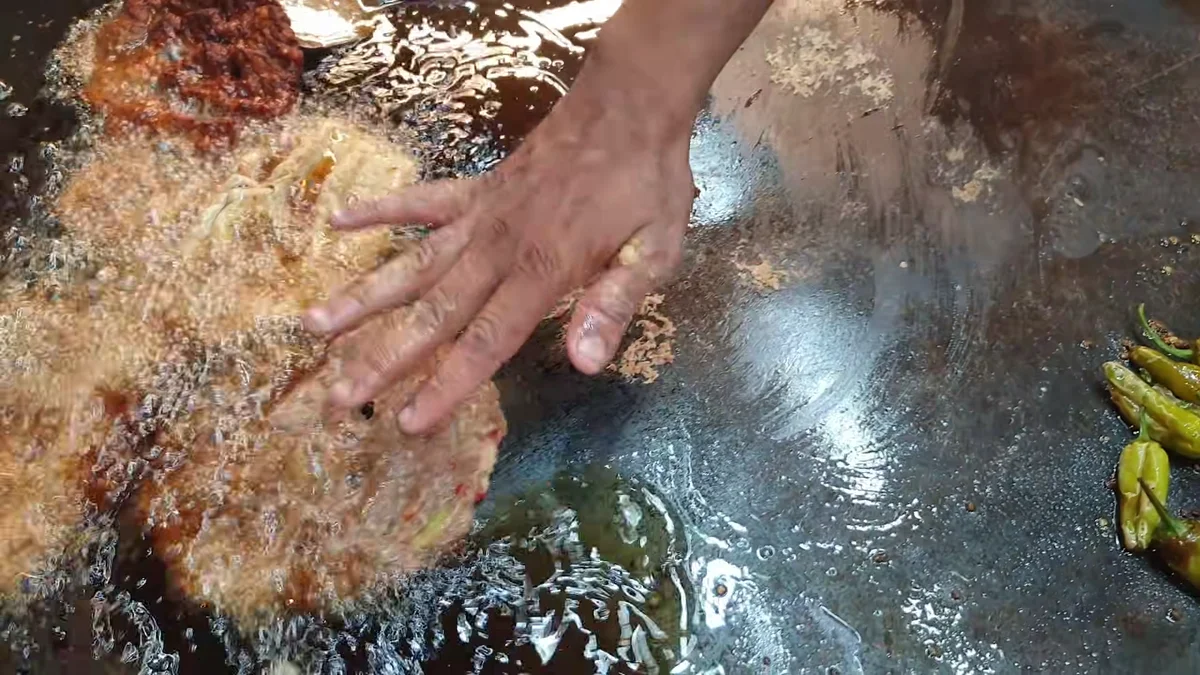 Pressing a chapli kabab flat in hot ghee