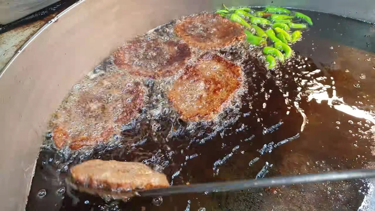 Chapli kababs frying in ghee with green chillies