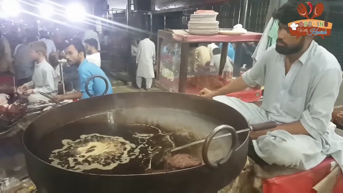 Chapli kabab frying in a large wok of hot fat