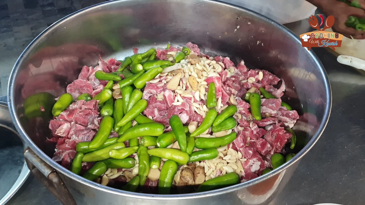 Beef pieces and green chillies in a large steel pot