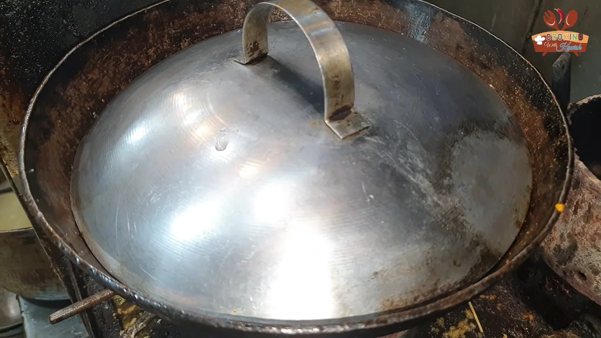 Karahi covered with a lid while the tomatoes soften