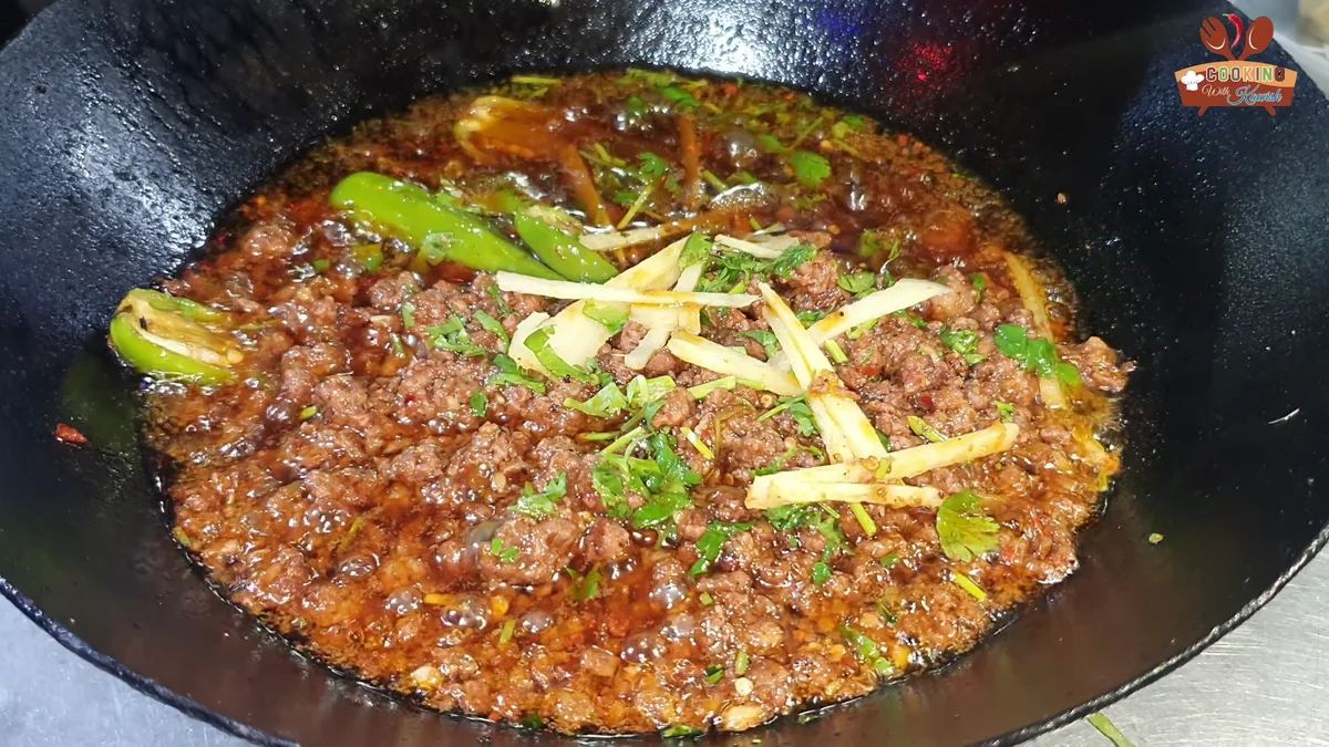 Dum keema in a karahi topped with ginger julienne and green chillies
