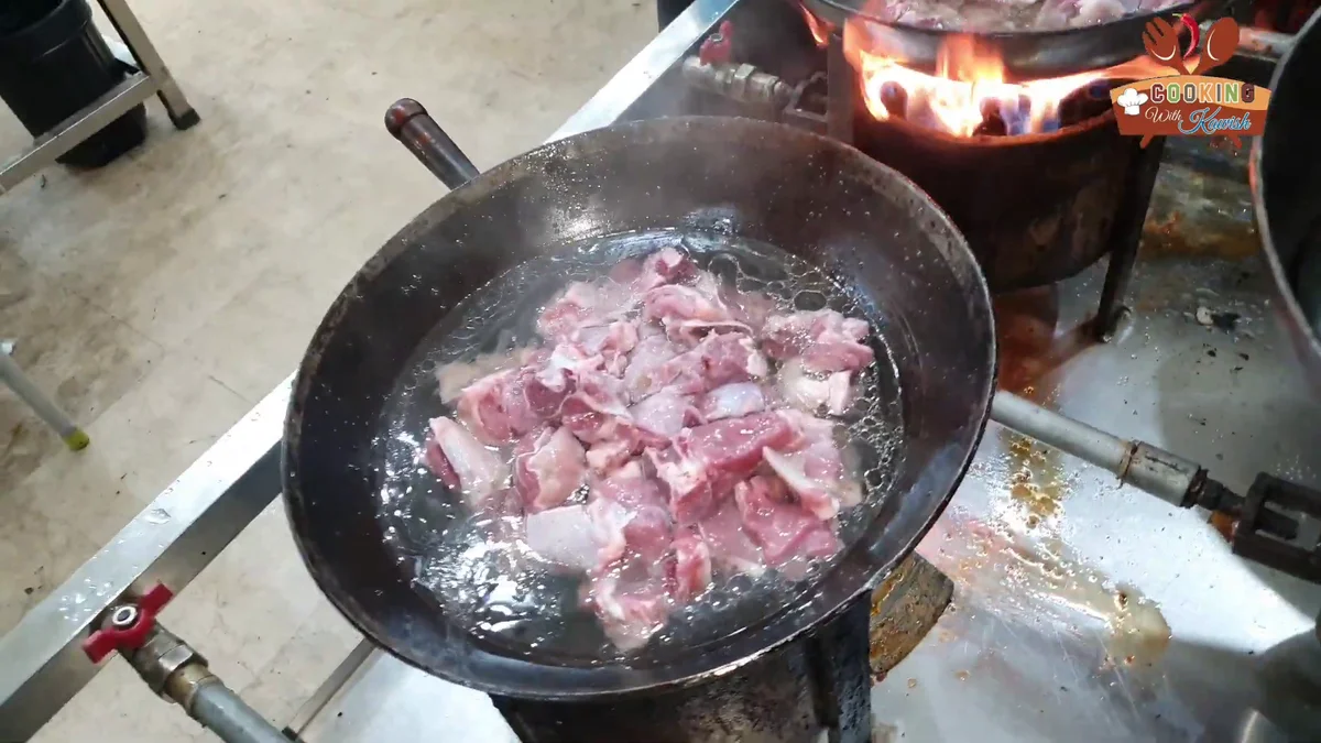 Mutton with water in the karahi at the start of the braise