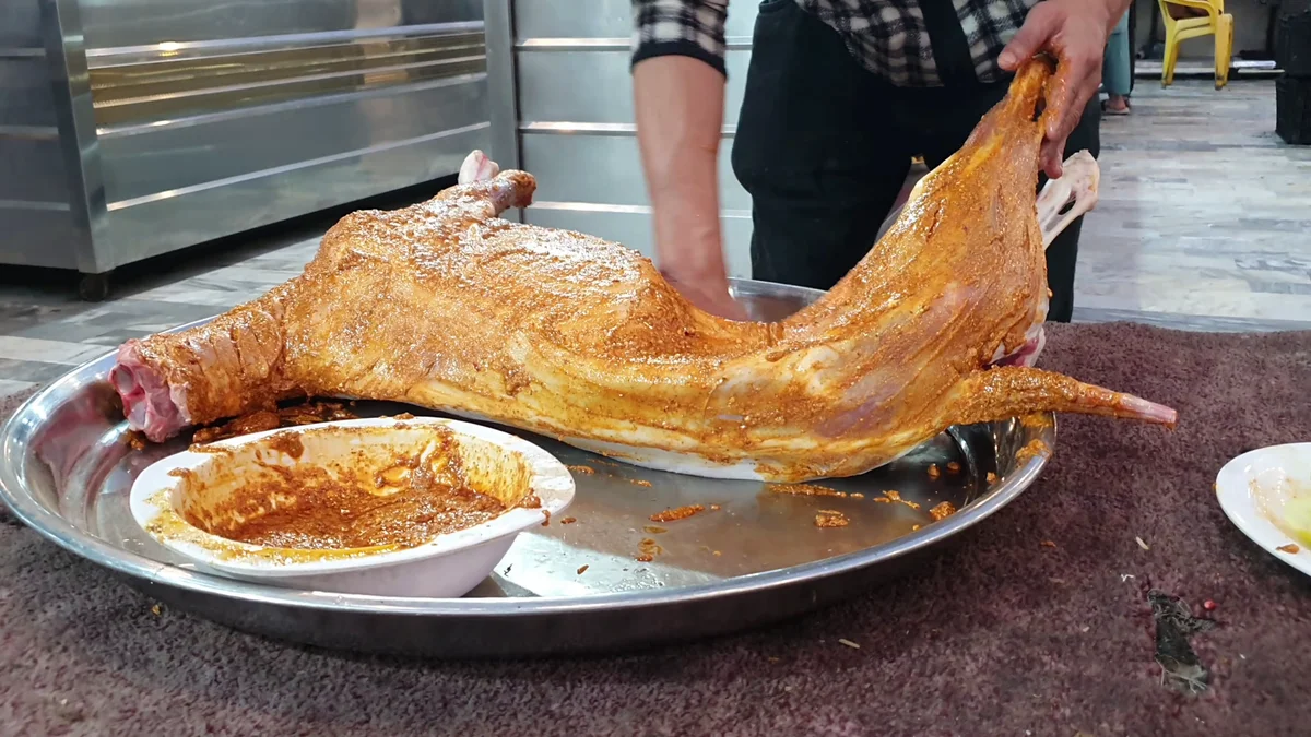 Whole mutton coated in orange masala before steaming