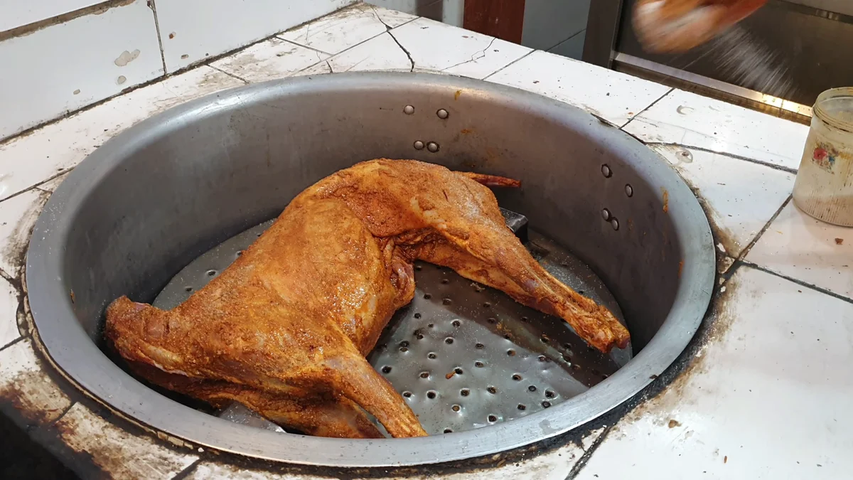 Coated mutton placed in a large pot with a perforated base